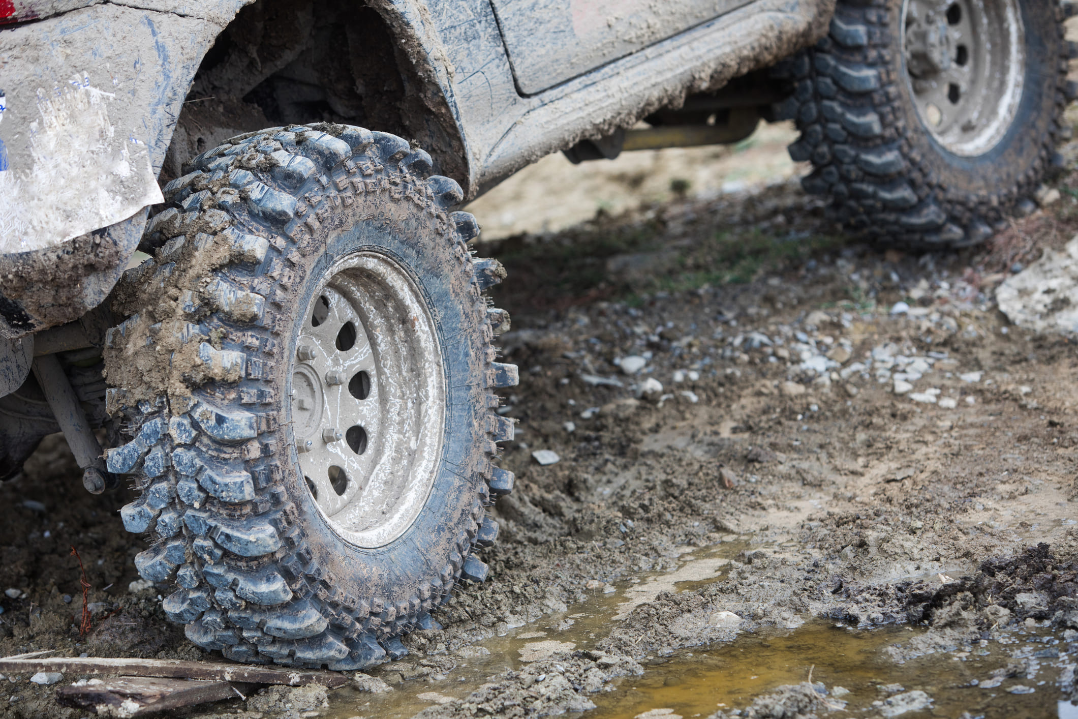 Close-up 4x4 vehicle driving through the mud.