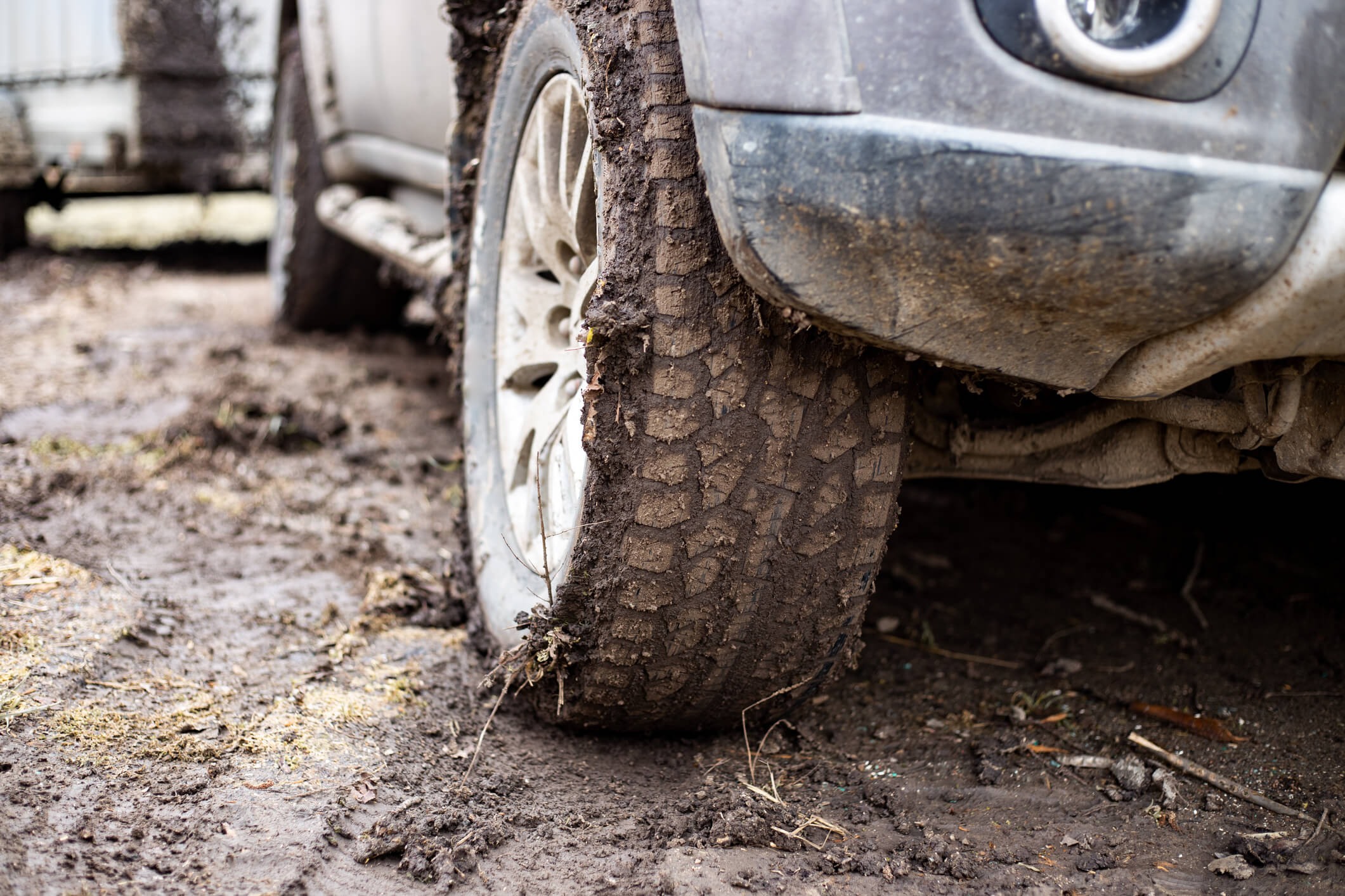 Close-up front-view of an off-road vehicle with muddy wheels.